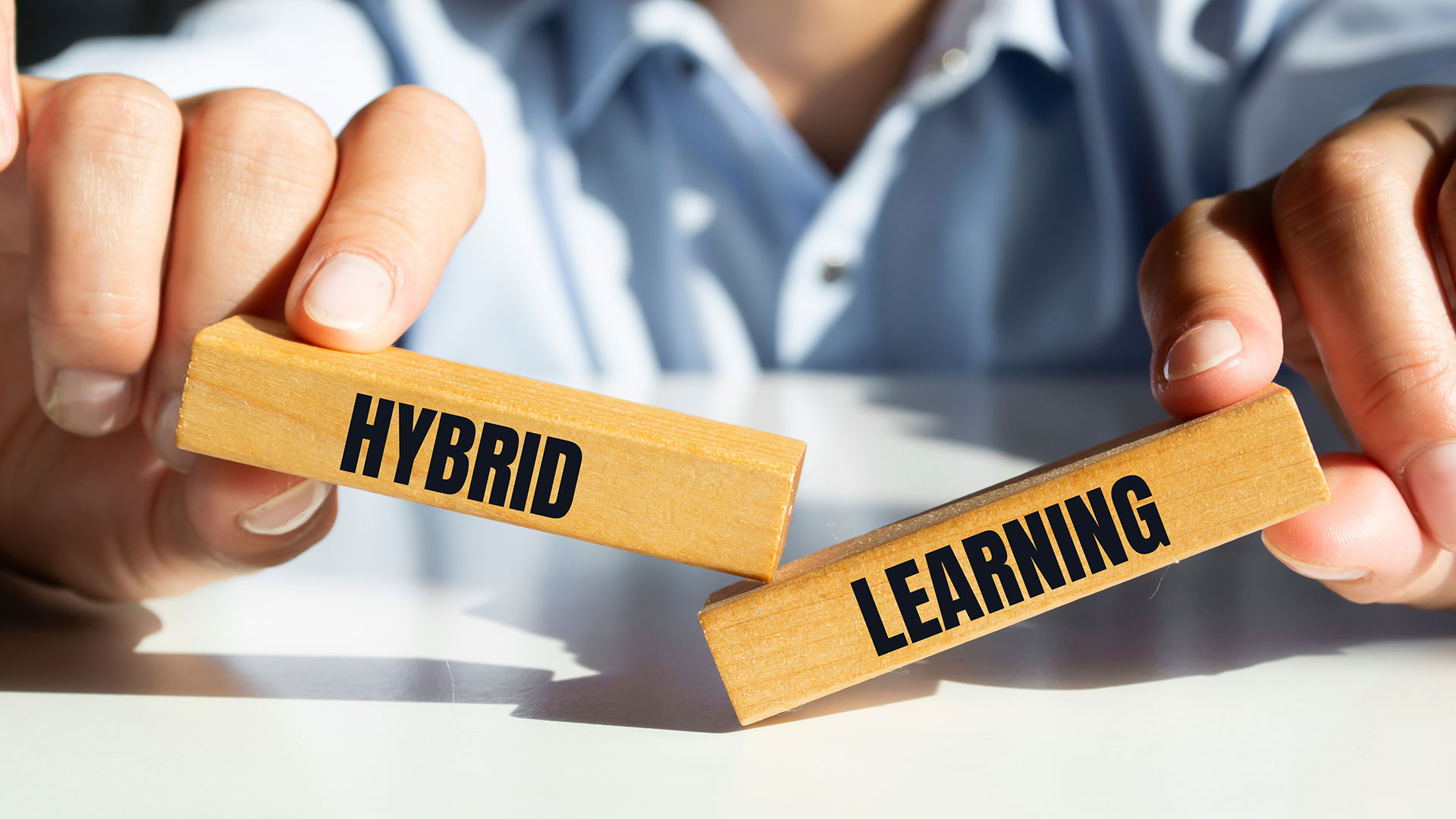 Person holding two blocks that spell Hybrid Learning.